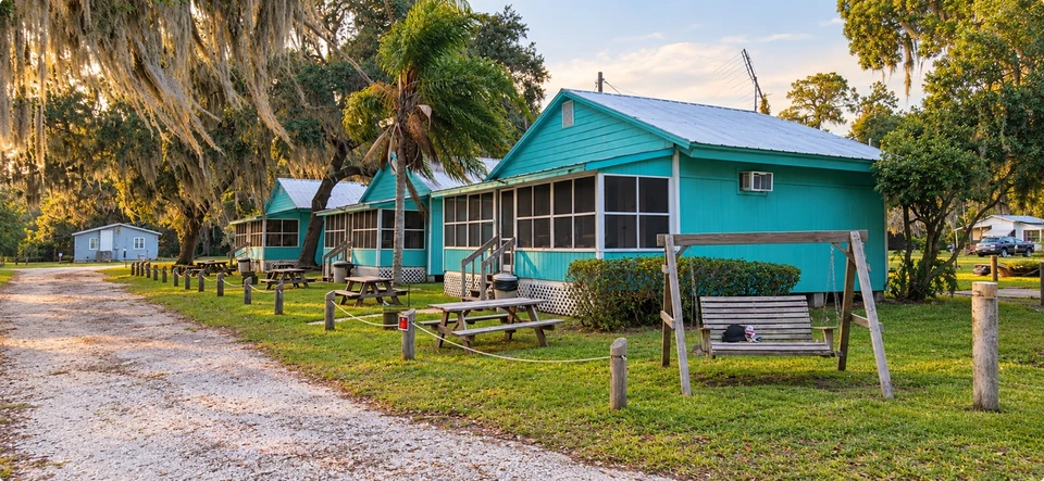 Turquoise cabins with screened porches, picnic tables and live oaks